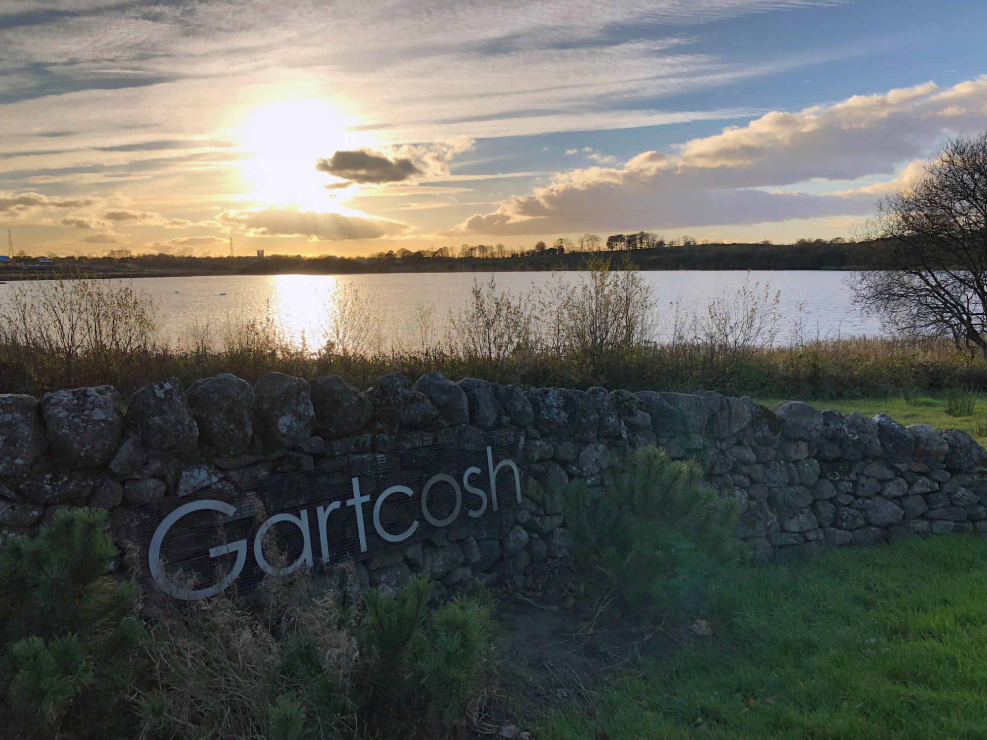 Gartcosh sign with Johnston Loch and dramatic sunset in background